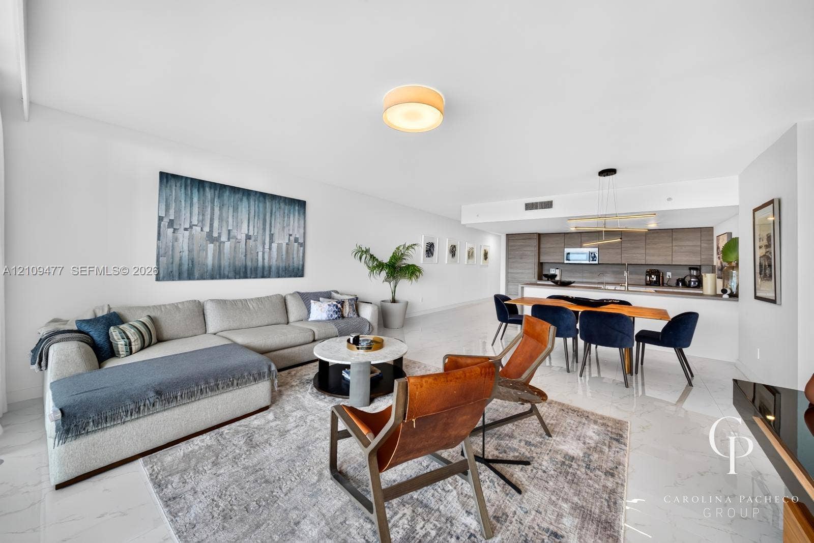 Open floor plan featuring polished stone-finish flooring, custom horizontal-grain cabinetry, quartz countertops, minimalist recessed lighting, and a modern tiered chandelier