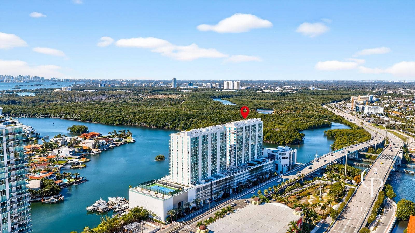 High-rise residential building featuring a swimming pool, tennis court, and immediate proximity to waterfront areas