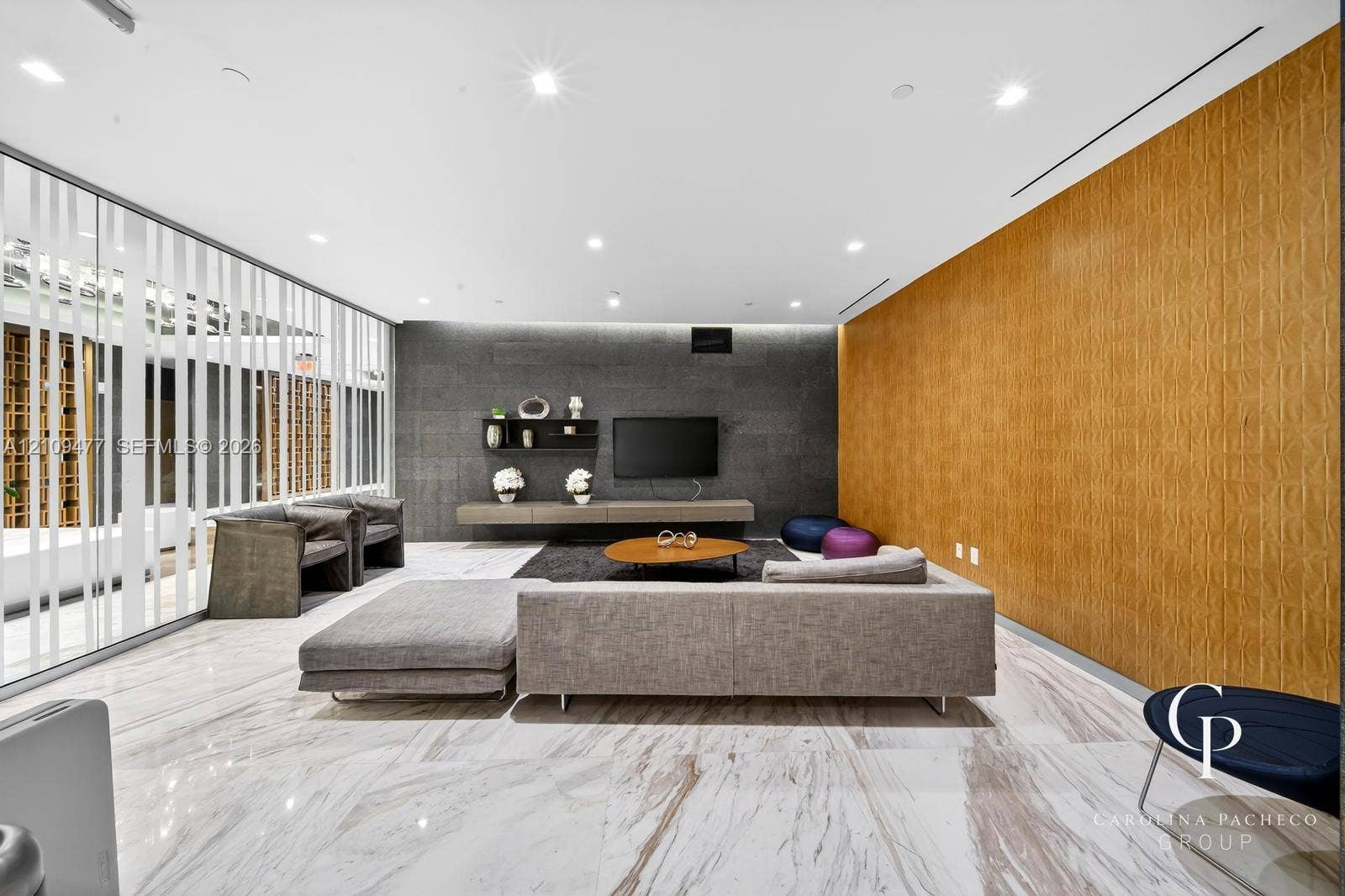 Large-format polished stone flooring, custom wood-paneled accent wall, dark stone-clad feature wall, floating built-in cabinetry, and full-height glass screen