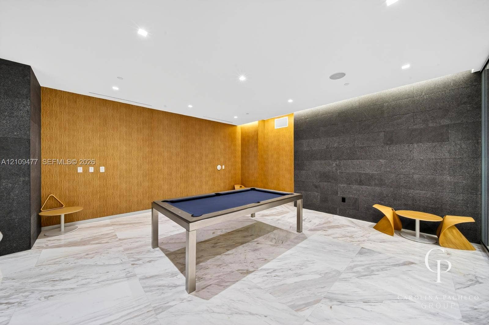Interior space featuring large-format stone floor tiles, natural wood-finish wall paneling, charcoal-toned stone feature walls, and recessed ceiling lighting