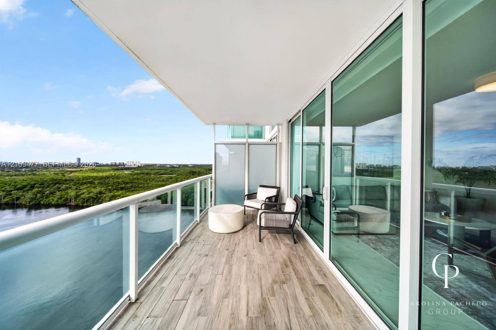 Covered balcony with wood-finish flooring, glass panel railings, and floor-to-ceiling sliding glass doors