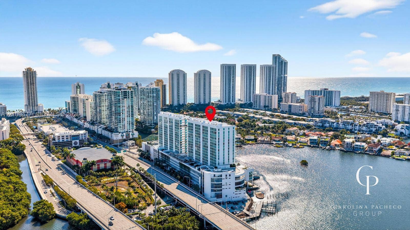 High-rise coastal residential building featuring extensive glass-panel balconies, positioned on the waterfront with immediate access to a deep-water canal