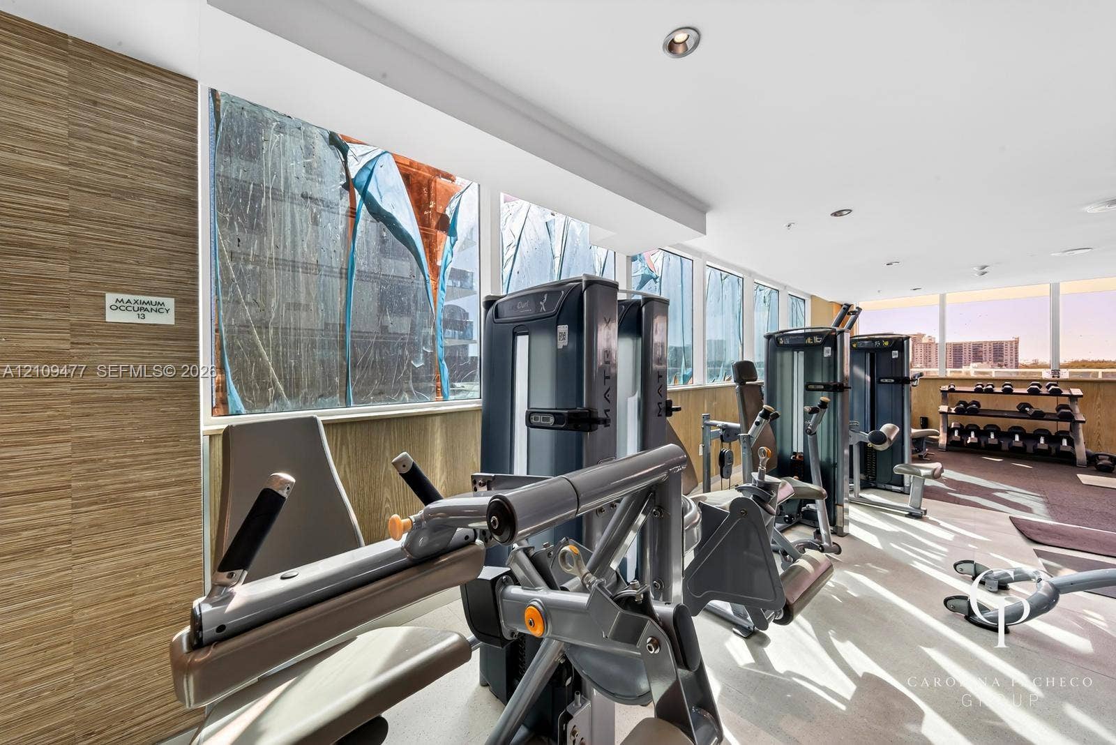 Fitness center featuring floor-to-ceiling windows, wood-finish wall paneling, and recessed lighting