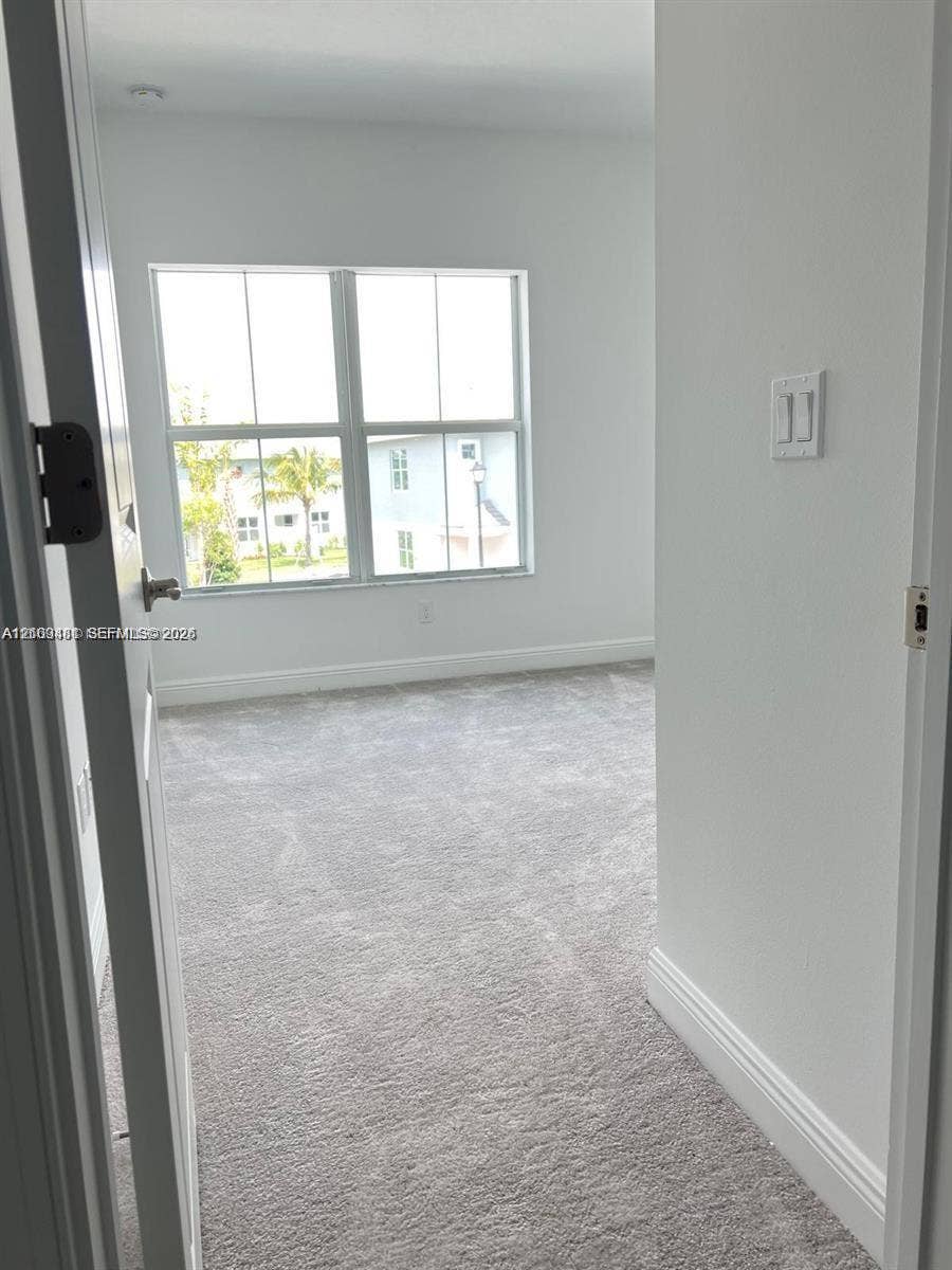 Room interior featuring neutral wall-to-wall carpeting and multi-pane windows