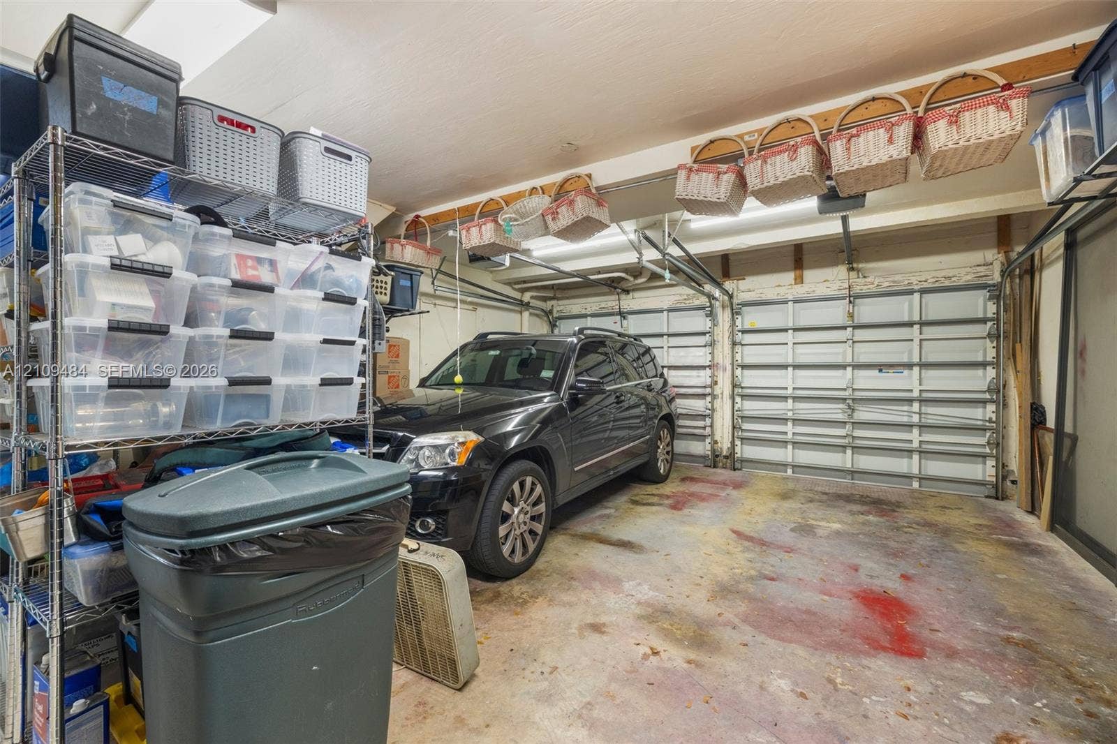 Two-car garage featuring segmented overhead doors and exposed ceiling beams with mounted storage