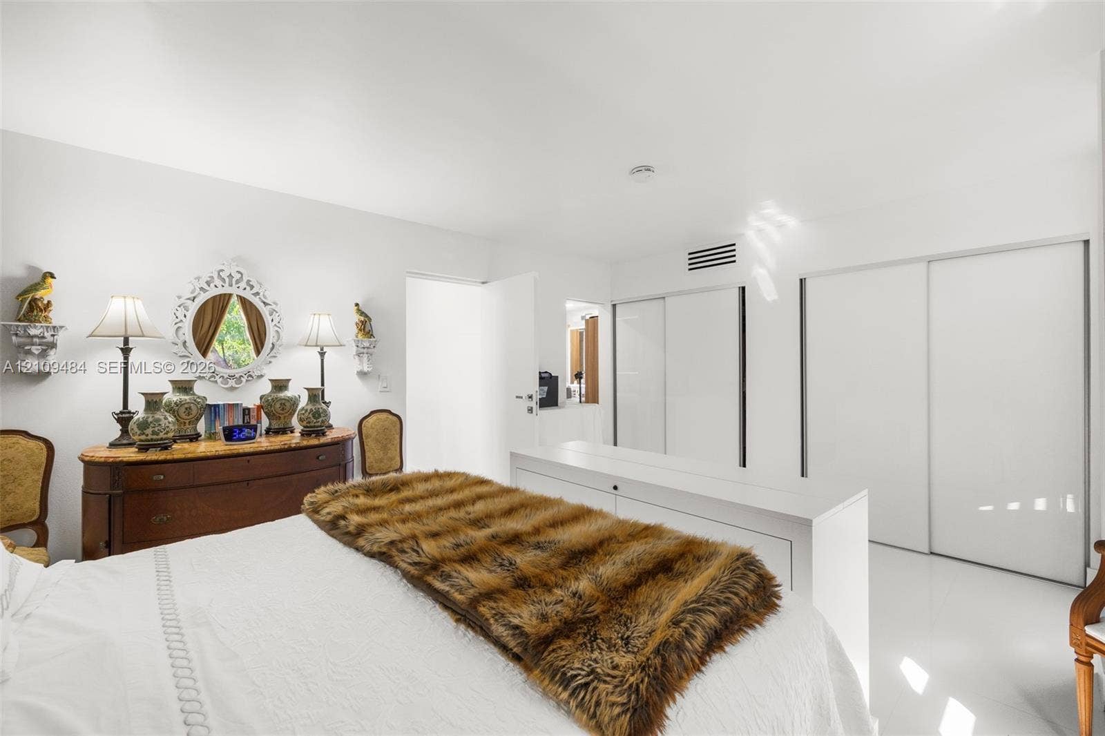 Minimalist interior featuring high-gloss flooring, recessed lighting, and dual floor-to-ceiling closets with sliding doors