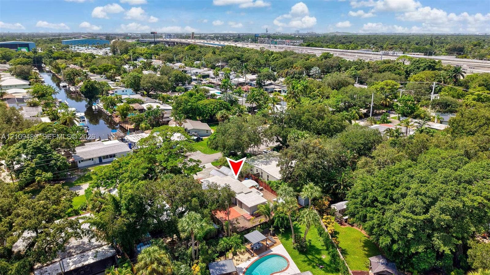 Fort Lauderdale, FL 33312 Aerial perspective of a property featuring an in-ground swimming pool, stone-paver pool deck, mature landscaping, and waterfront canal access