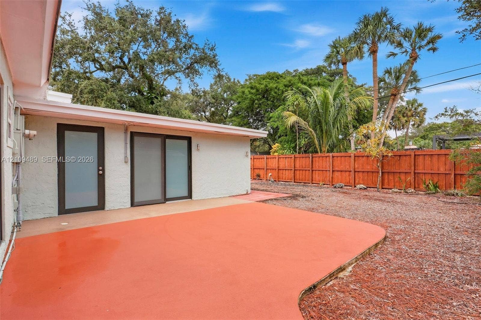 Fort Lauderdale, FL 33312 Stucco exterior featuring a stained concrete patio, frosted glass door, sliding glass door, and wooden privacy fencing