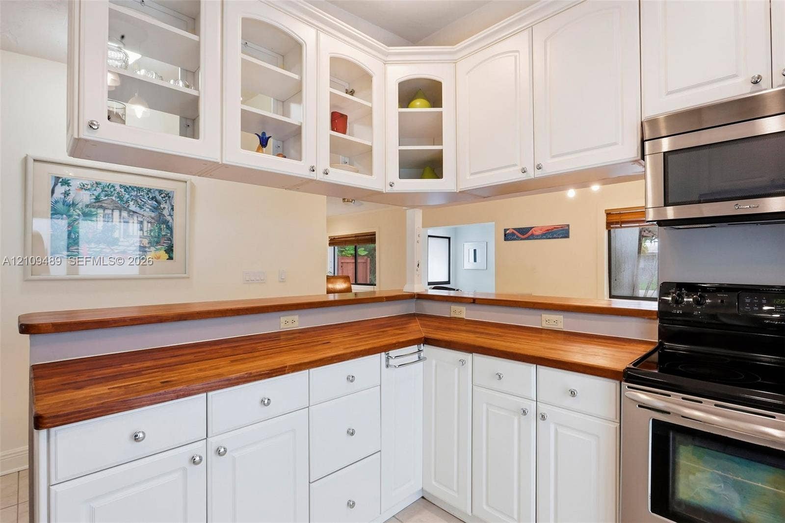 Fort Lauderdale, FL 33312 Kitchen featuring white cabinetry with glass-front uppers, natural wood-finish countertops, and stainless steel appliances
