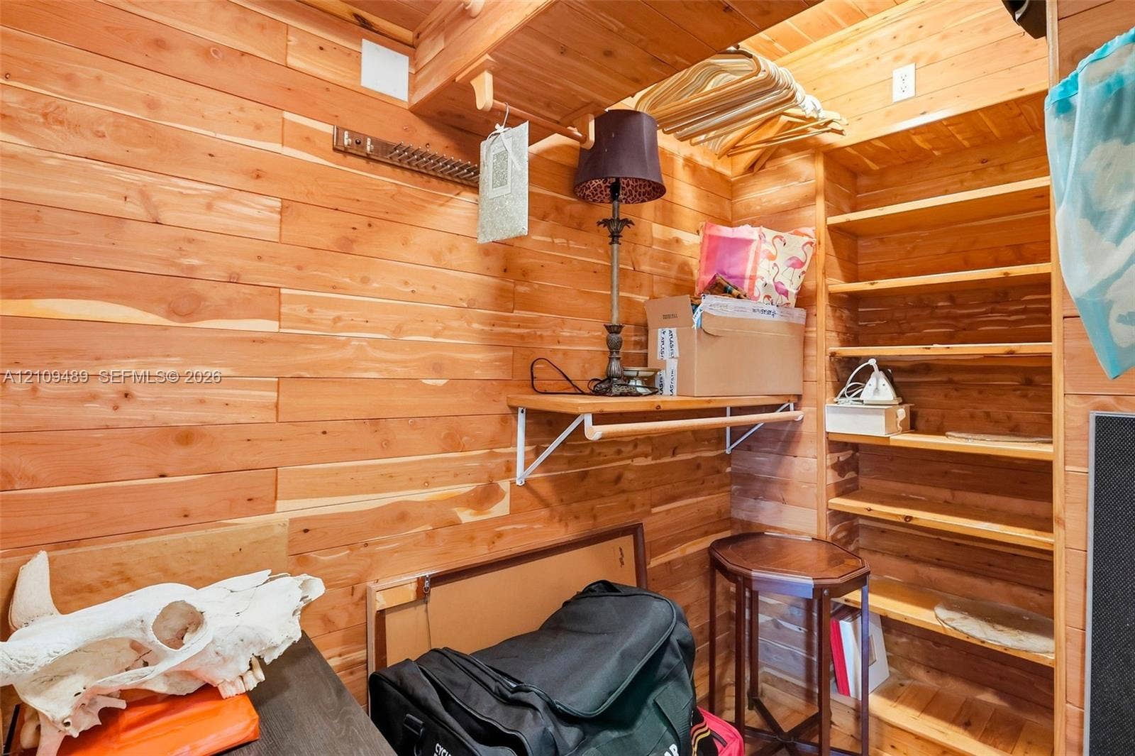 Fort Lauderdale, FL 33312 Storage space featuring natural wood-plank wall paneling, built-in wooden shelving, and fixed wooden hanging rods