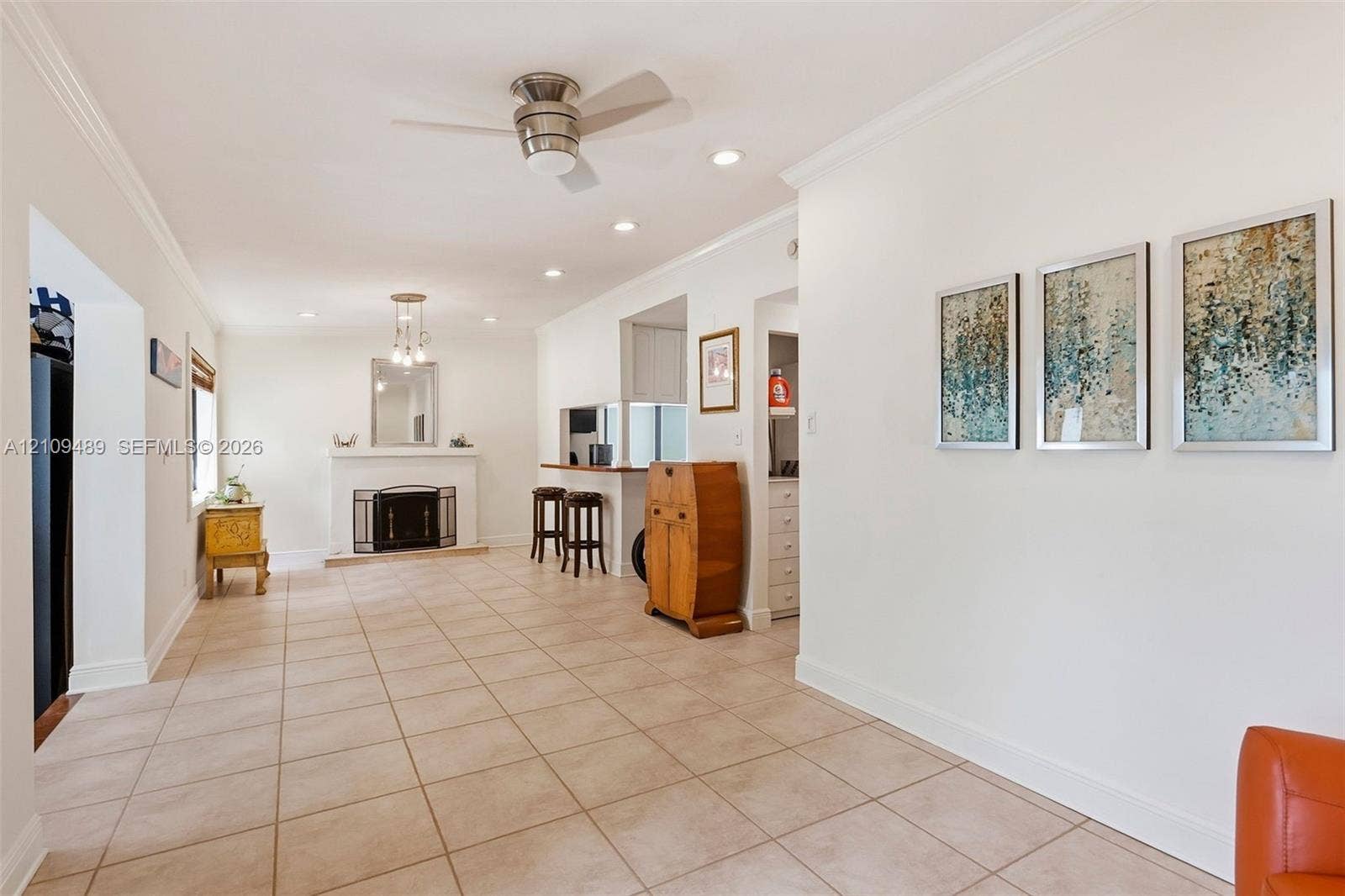 Fort Lauderdale, FL 33312 Open interior space featuring light-toned tile flooring, recessed lighting, a ceiling fan, crown molding, and a fireplace with a mantel