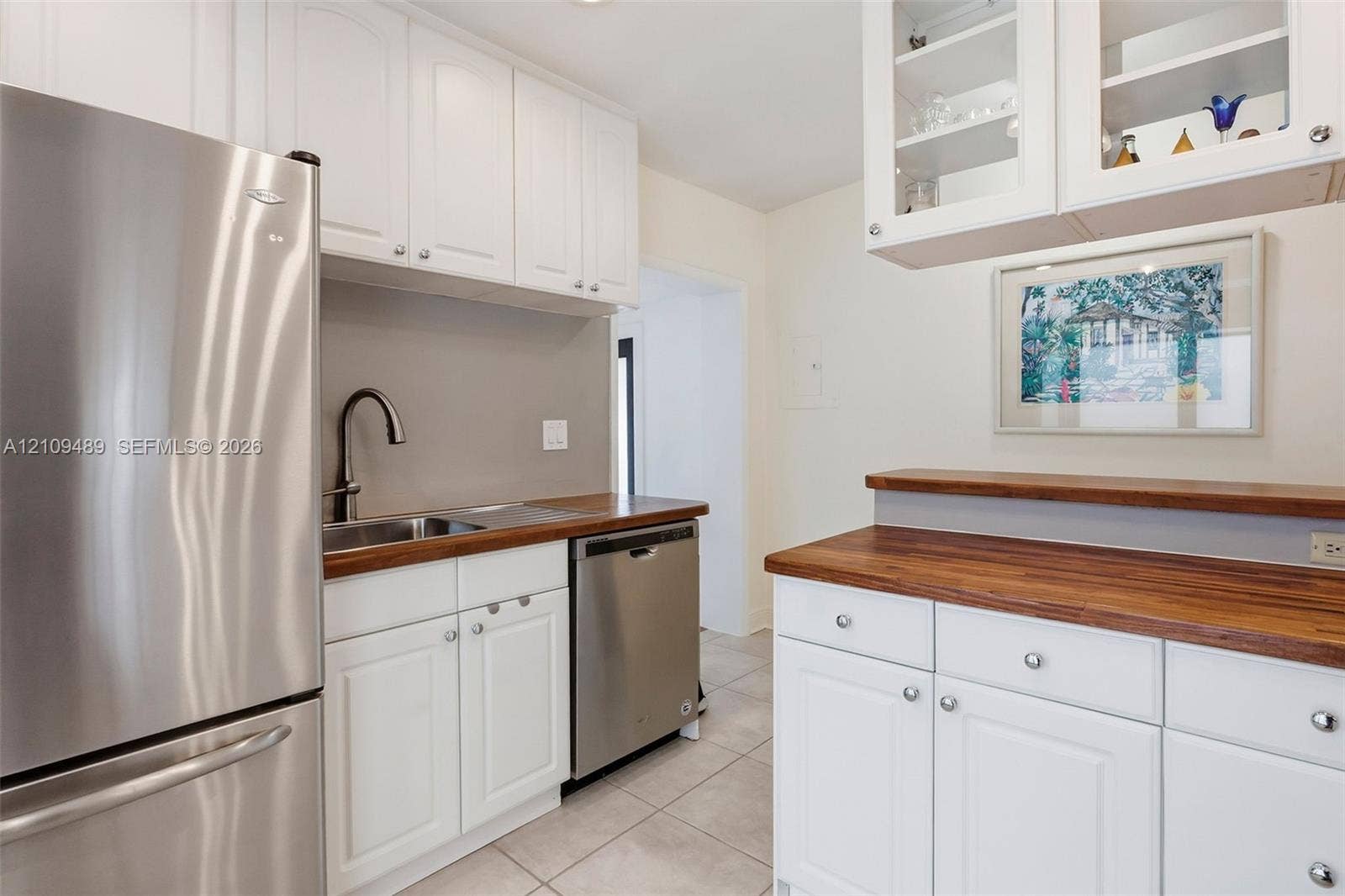 Fort Lauderdale, FL 33312 Kitchen featuring white shaker-style cabinetry, wood-finish countertops, stainless steel appliances, a high-arc faucet, and upper glass-front display cabinets