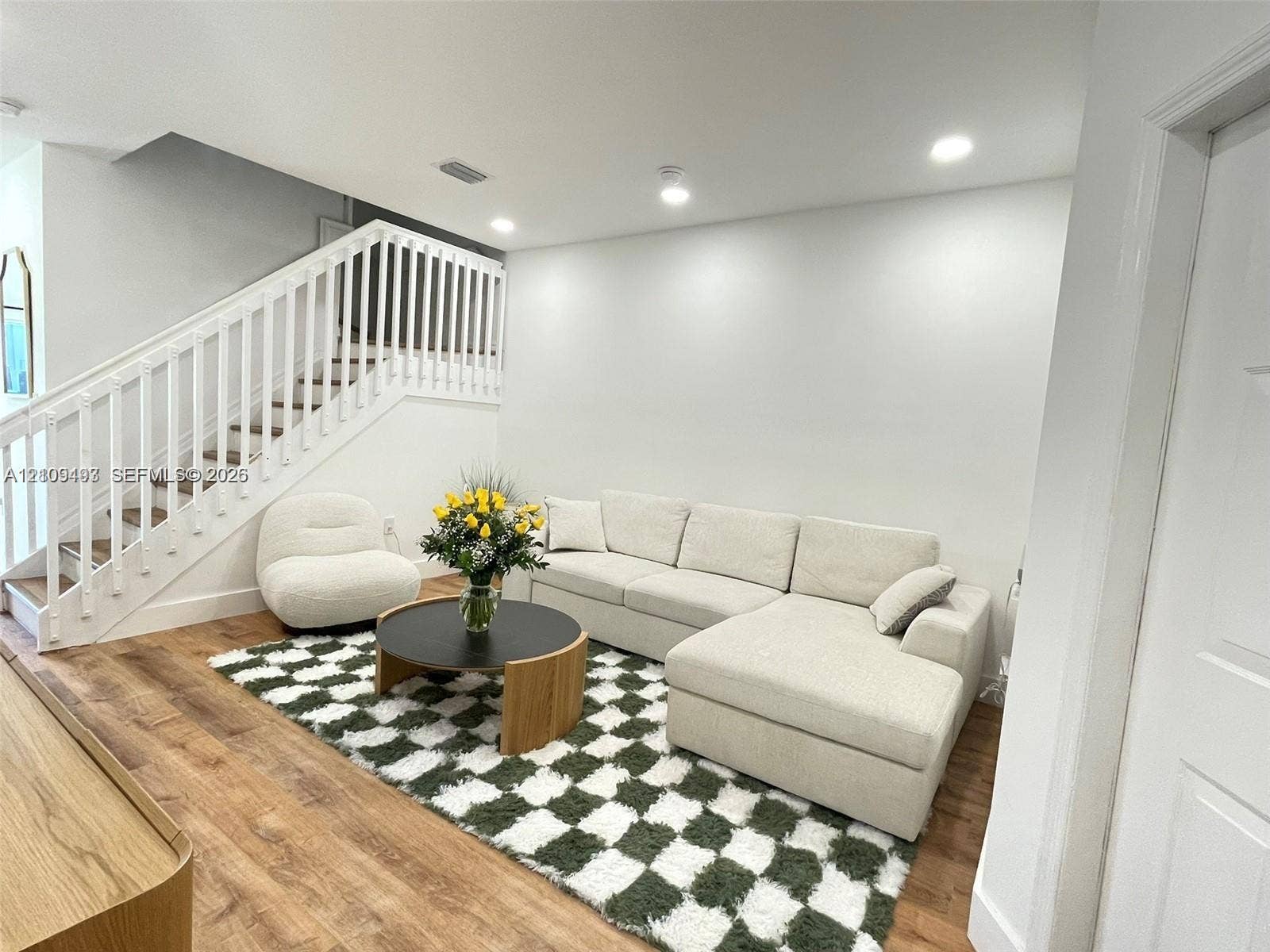 Staircase featuring a white balustrade and wood-finish flooring, complemented by recessed ceiling lighting