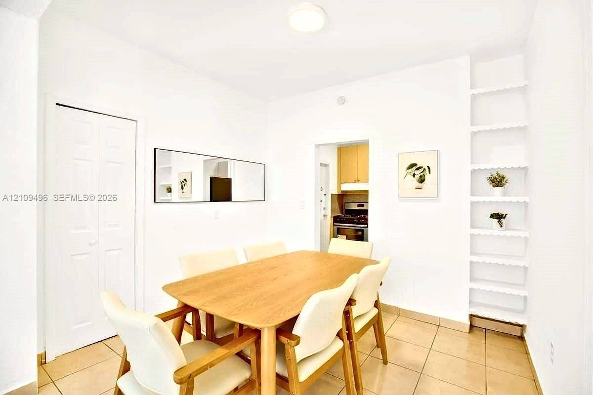 Dining space featuring ceramic tile flooring, built-in recessed shelving, a flush-mount ceiling light fixture, and a multi-panel closet door
