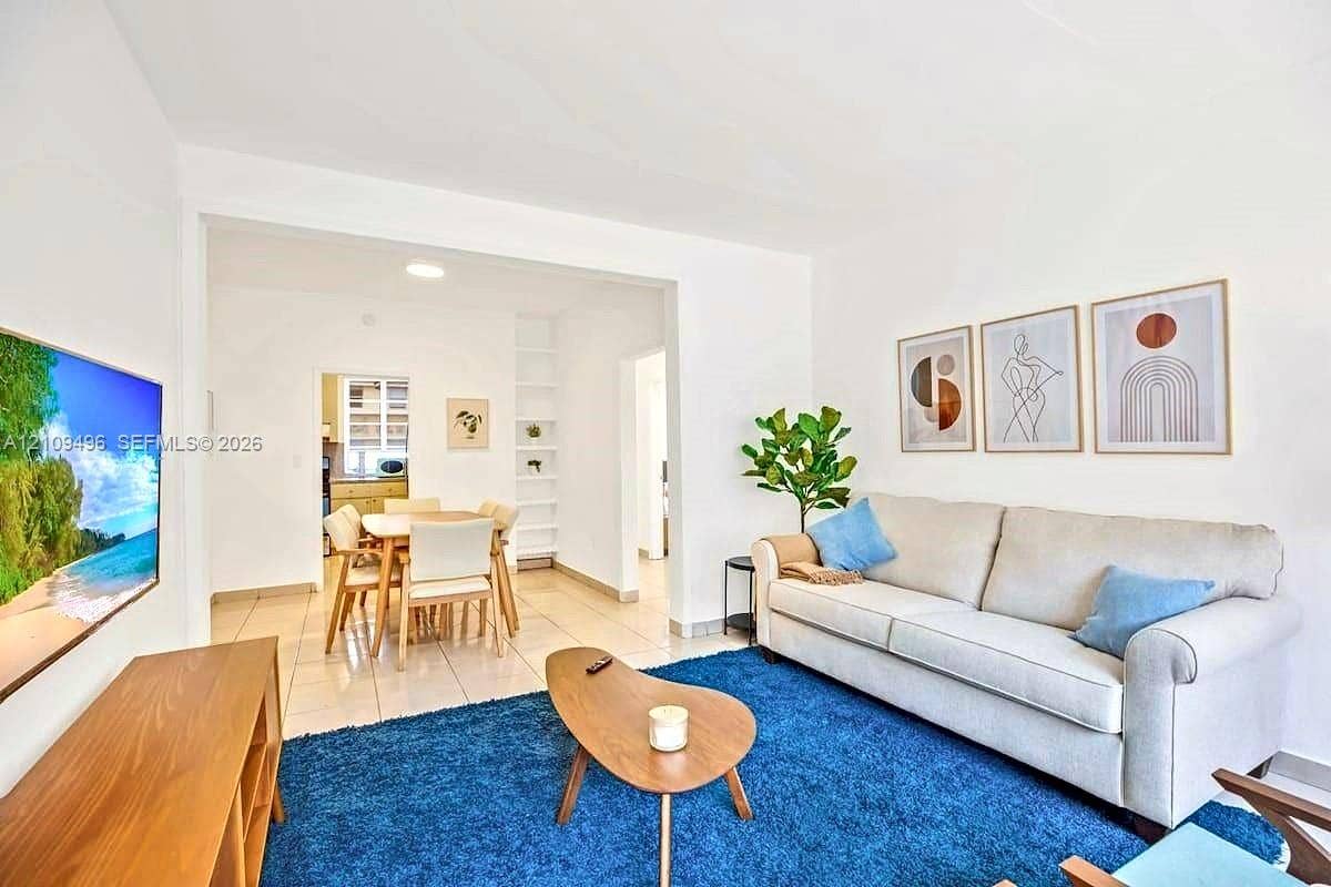 Living area featuring light-toned tile flooring and built-in floor-to-ceiling shelving
