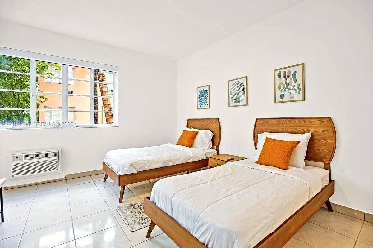 Bright room featuring light-colored tile flooring, smooth white walls, and a large multi-pane window