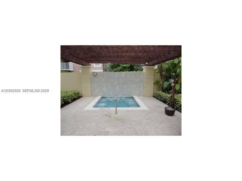6804 W Sample Road, #6804, Coral Springs, Coral Springs, FL 33067 In-ground spa featuring a stone water feature, wood-slat pergola, paved patio surround, and privacy wall