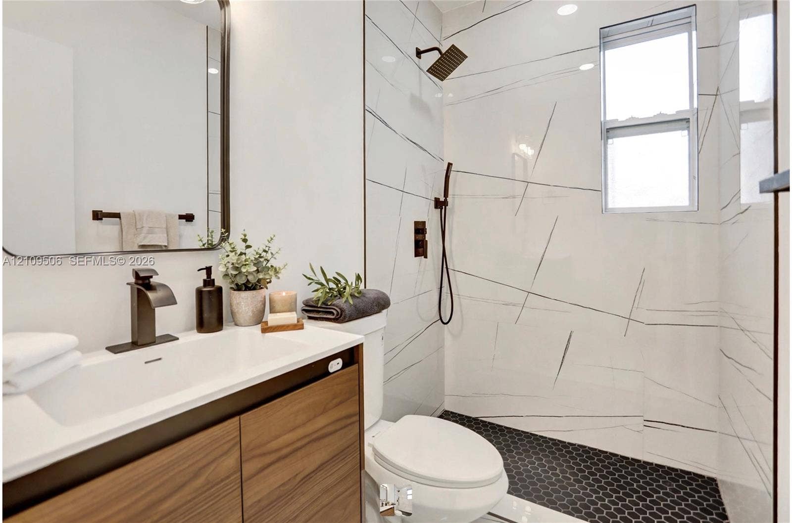 708 N 20th, #1-2, Hollywood, Hollywood, FL 33020 Wood-finish vanity with a rectangular sink, large-format tile shower surround featuring stone-style veining, matte black hardware, and black hexagonal floor tile