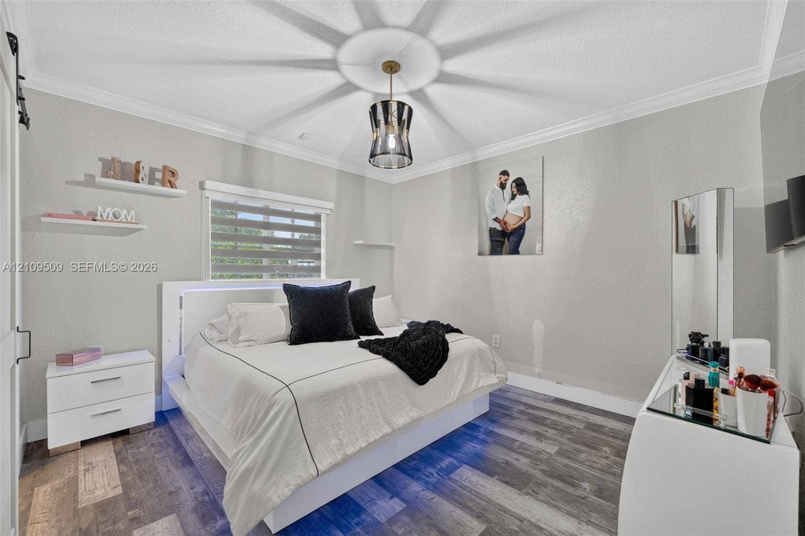 7721 NW 201st Terrace, Hialeah, FL 33015 Bedroom featuring wood-finish flooring, crown molding, tiered window shades, and a ceiling-mounted pendant light fixture