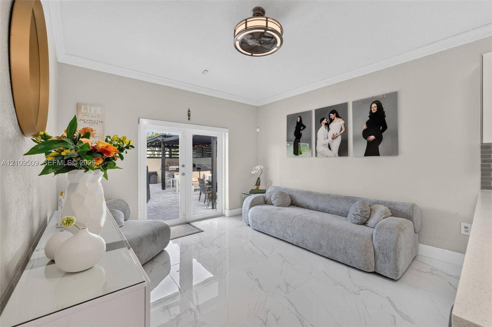 7721 NW 201st Terrace, Hialeah, FL 33015 Polished tile flooring, crown molding, circular semi-flush mount lighting, and French doors leading to a paved patio area