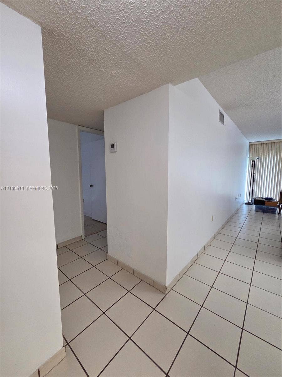 11081 NW 7th Street, #101-14, Miami, FL 33172 Interior area featuring neutral-toned tile flooring and vertical blinds