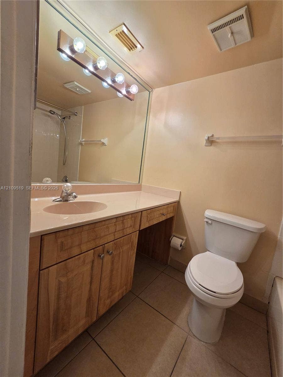 11081 NW 7th Street, #101-14, Miami, FL 33172 Bathroom featuring a vanity with wood-finish cabinetry, a solid-surface countertop, an integrated sink, a full-width wall mirror, and tiled flooring