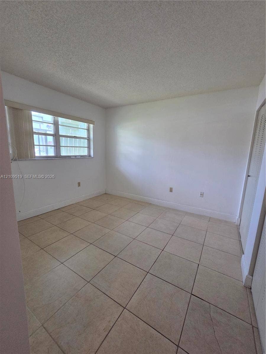 11081 NW 7th Street, #101-14, Miami, FL 33172 Interior room featuring neutral ceramic tile flooring, textured ceiling finish, and a window with horizontal blinds
