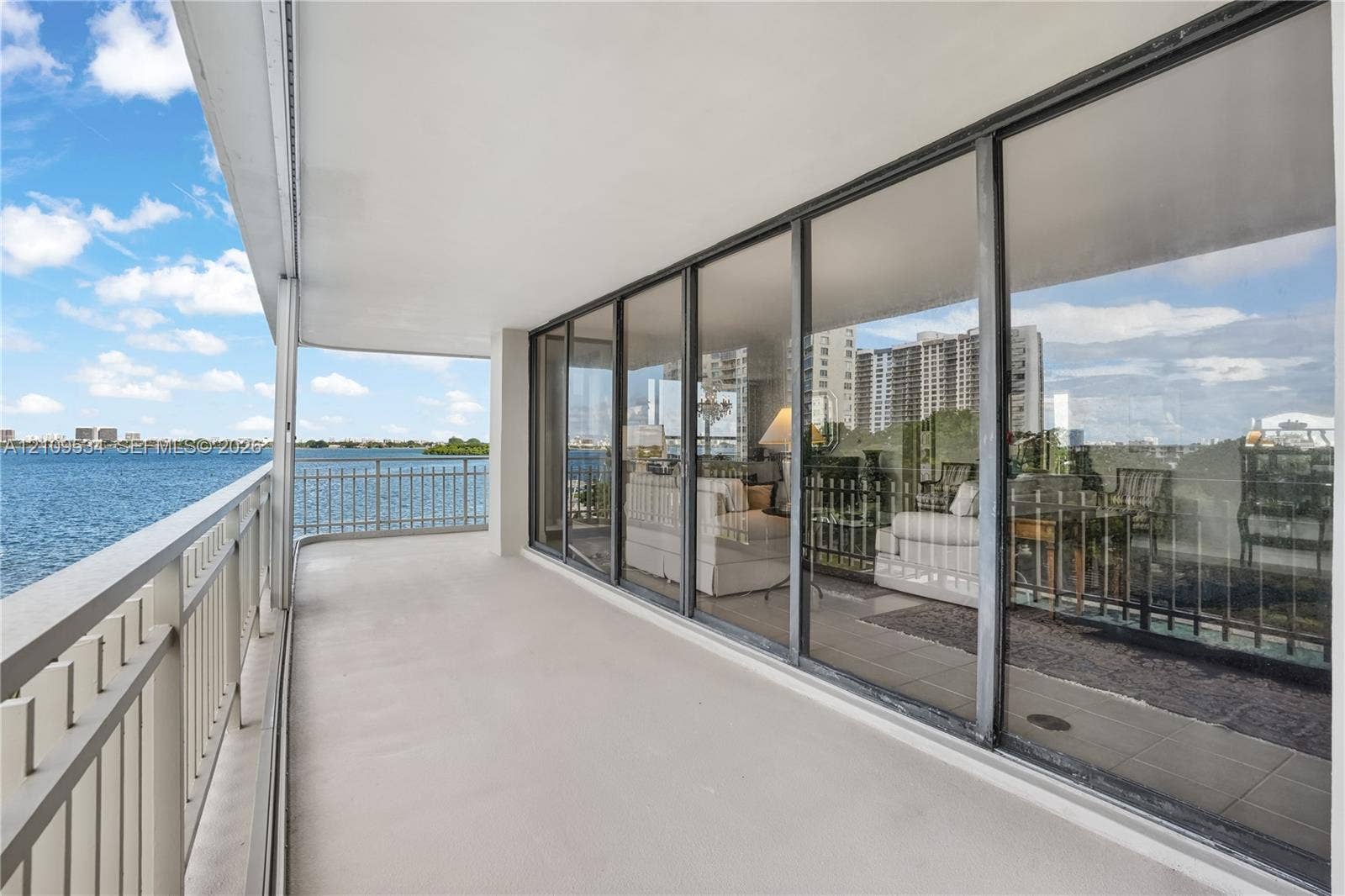 Covered balcony featuring a metal railing, concrete flooring, and full-height sliding glass doors