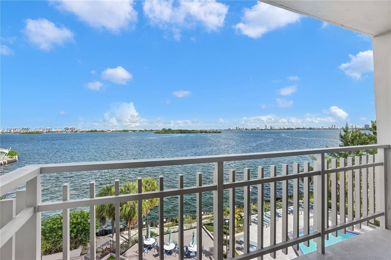 Covered balcony featuring white vertical railings and open-air exposure, overlooking expansive water scenery