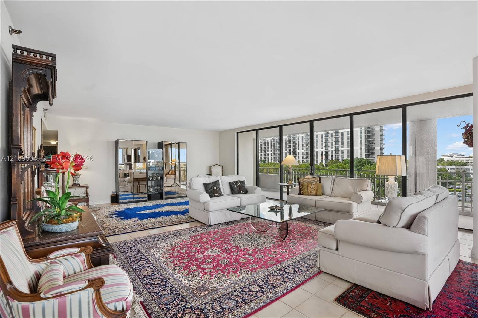 Living area featuring floor-to-ceiling glass sliding doors, neutral tile flooring, and a private balcony