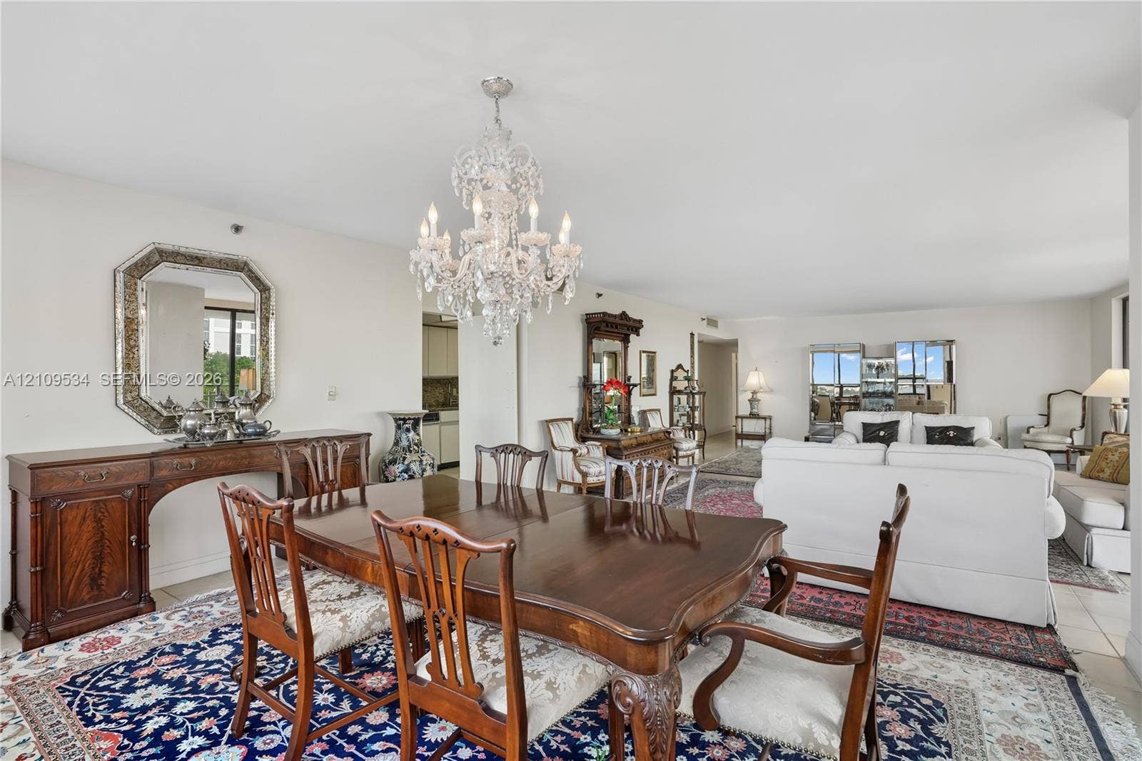 Open-concept living space featuring a tiered crystal chandelier, neutral wall paint, and tile flooring