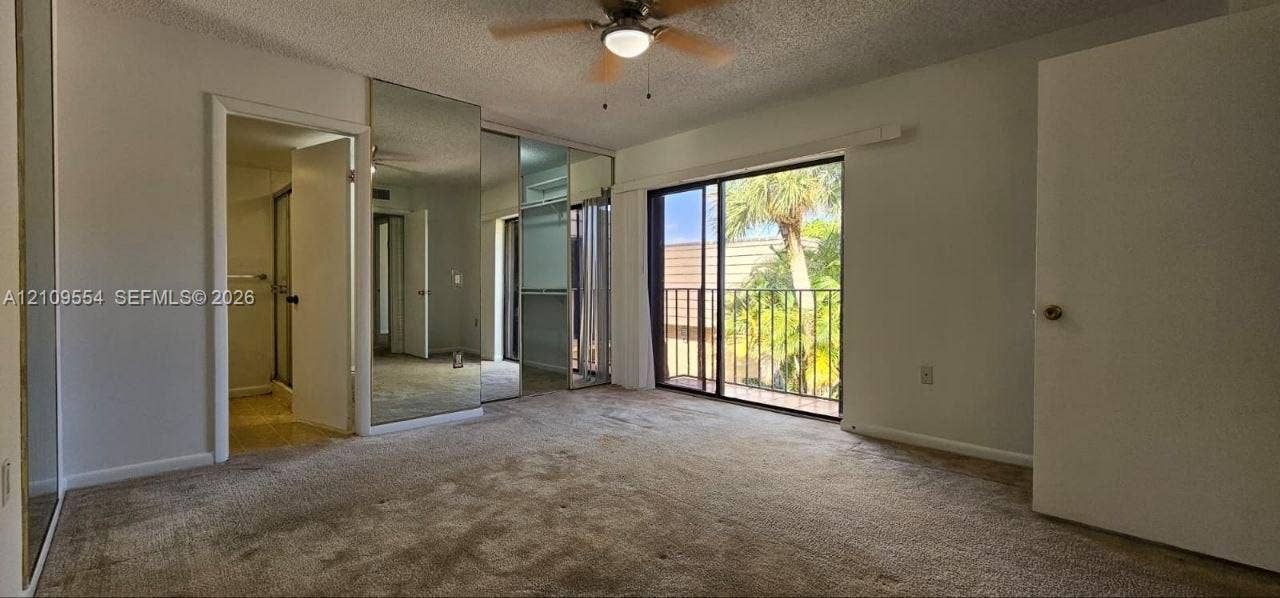 1802 18th Way, #1802, West Palm Beach, West Palm Beach, FL 33407 Sliding glass door opening to a private balcony, floor-to-ceiling mirrored closet doors, neutral wall-to-wall carpeting, and a ceiling-mounted light fixture