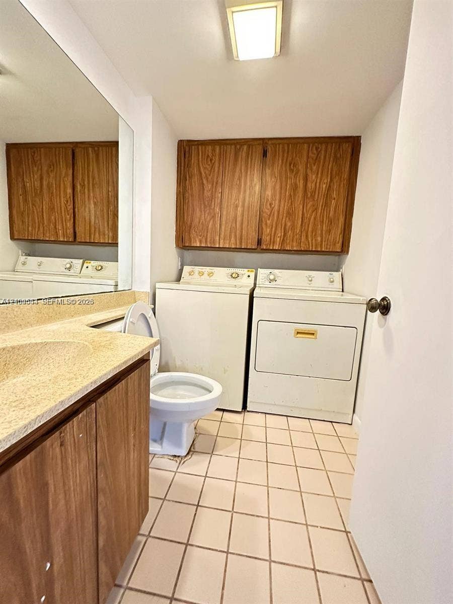 1802 18th Way, #1802, West Palm Beach, West Palm Beach, FL 33407 Utility space featuring ceramic tile flooring, built-in wood-finish cabinetry, a full-width vanity mirror, a countertop-integrated sink, and laundry hookups