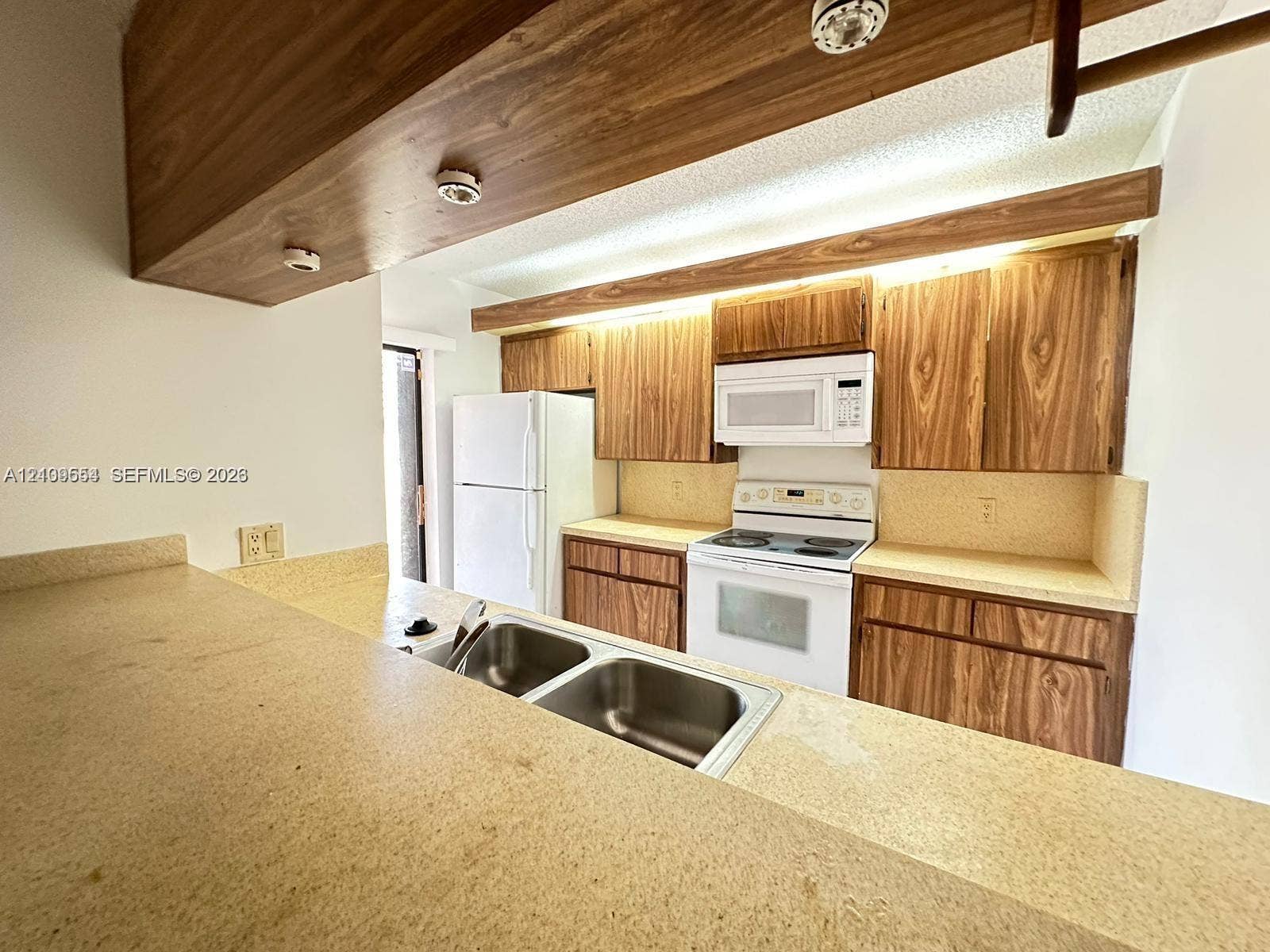 1802 18th Way, #1802, West Palm Beach, West Palm Beach, FL 33407 Kitchen featuring wood-grain cabinetry, solid surface countertops, a dual-basin stainless steel sink, and built-in appliances