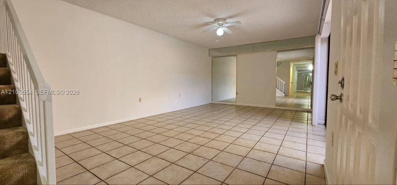 1802 18th Way, #1802, West Palm Beach, West Palm Beach, FL 33407 Ceramic tile flooring, carpeted staircase with white railings, ceiling fan with integrated lighting, and wall-mounted mirror panels