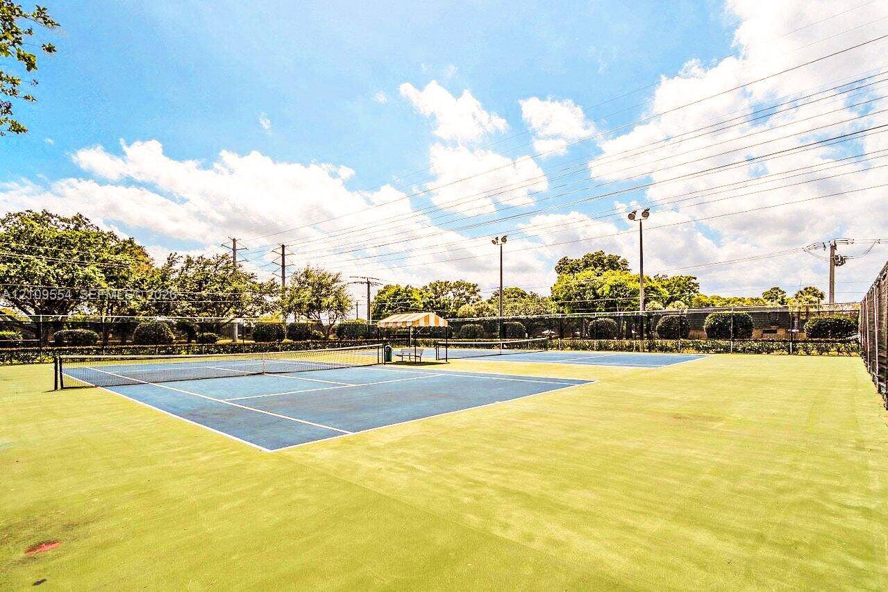 1802 18th Way, #1802, West Palm Beach, West Palm Beach, FL 33407 Multi-court tennis facility featuring blue hard-court surfaces, perimeter fencing, overhead lighting fixtures, and a shaded central seating area