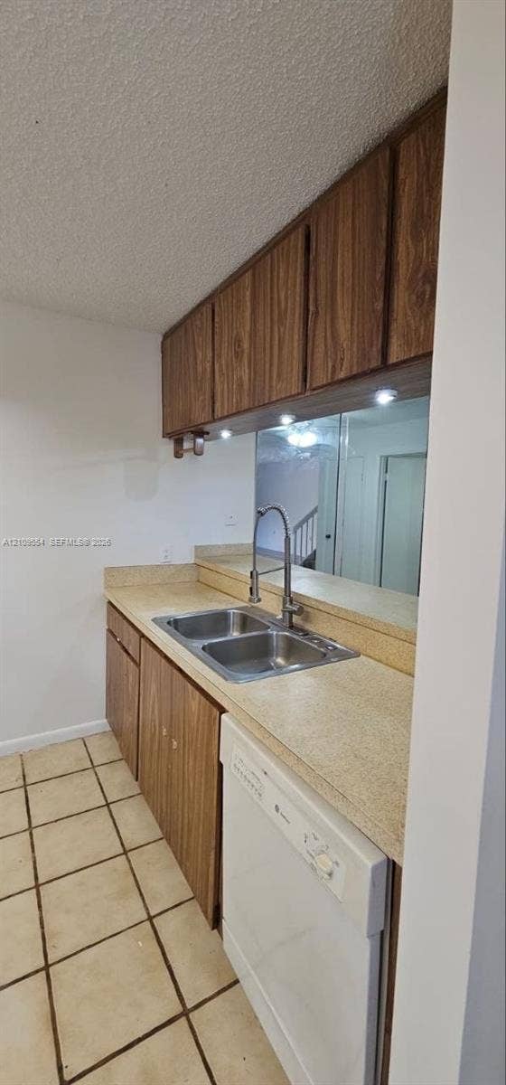 1802 18th Way, #1802, West Palm Beach, West Palm Beach, FL 33407 Kitchen featuring wood-finish cabinetry, neutral solid-surface countertops, dual-basin stainless steel sink with high-arch faucet, integrated dishwasher, and tiled flooring
