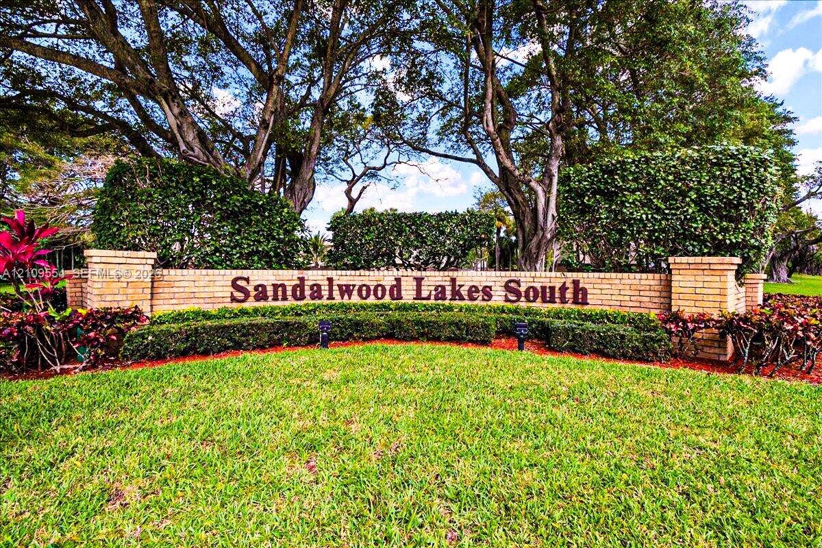 1802 18th Way, #1802, West Palm Beach, West Palm Beach, FL 33407 Brick monument signage featuring decorative stonework, mature trees, and manicured hedges