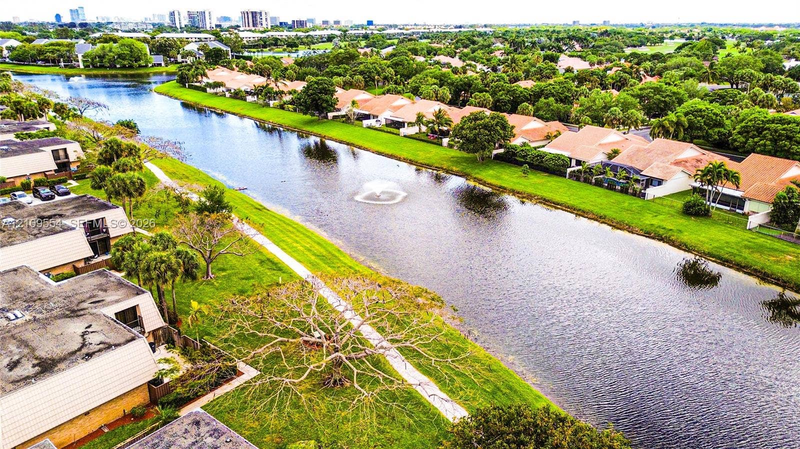 1802 18th Way, #1802, West Palm Beach, West Palm Beach, FL 33407 Aerial perspective of a multi-unit residential community featuring a central canal, water fountain, paved walkways, and mature landscaping