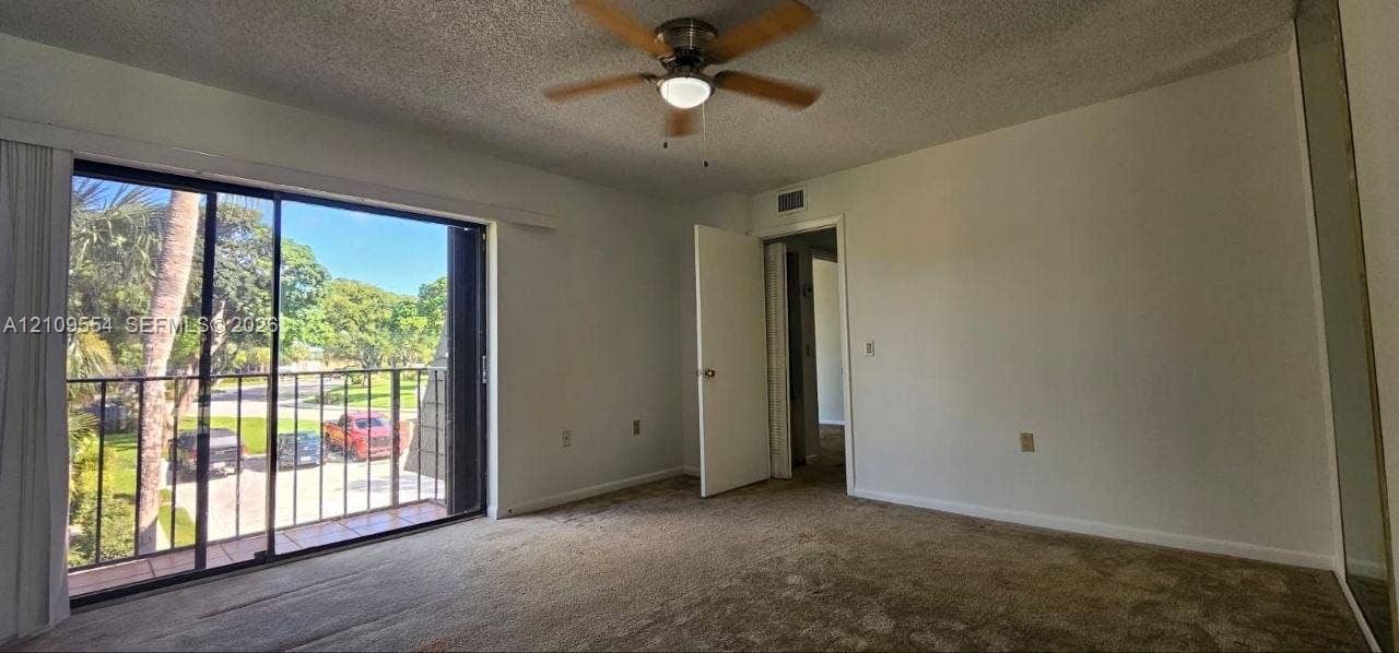 1802 18th Way, #1802, West Palm Beach, West Palm Beach, FL 33407 Interior space featuring floor-to-ceiling sliding glass doors, a private balcony with metal railing, wall-to-wall carpeting, and a ceiling-mounted light fixture with fan