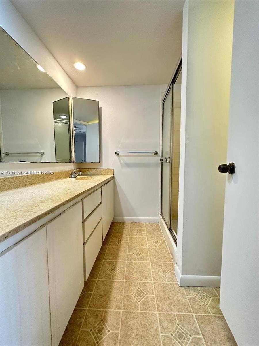 1802 18th Way, #1802, West Palm Beach, West Palm Beach, FL 33407 Bathroom featuring a full-width vanity with a neutral countertop, integrated sink, large wall-mounted mirror, and a walk-in shower with a glass enclosure