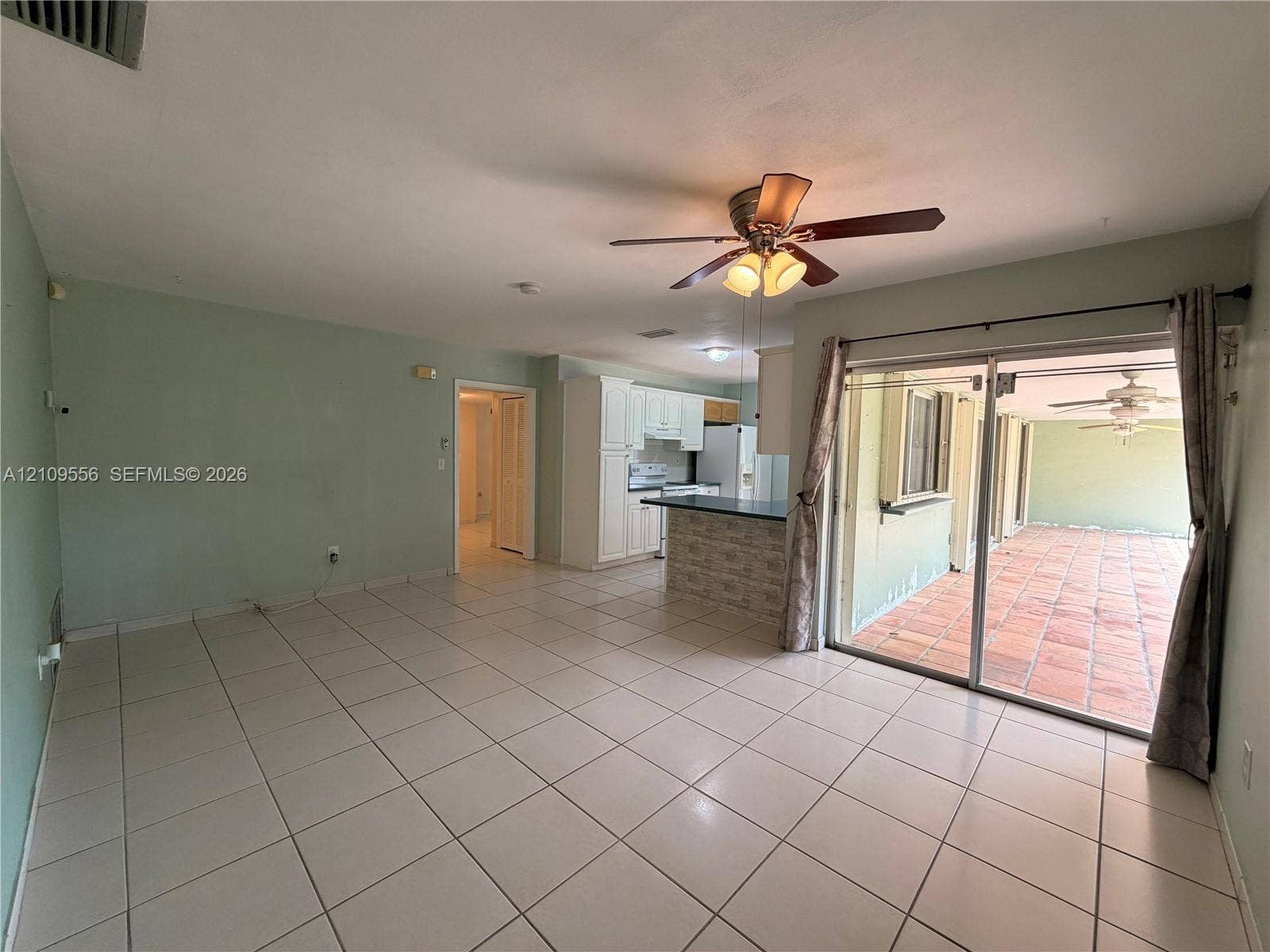 Living area featuring large format tile flooring, ceiling fan with light fixture, and floor-to-ceiling sliding glass doors