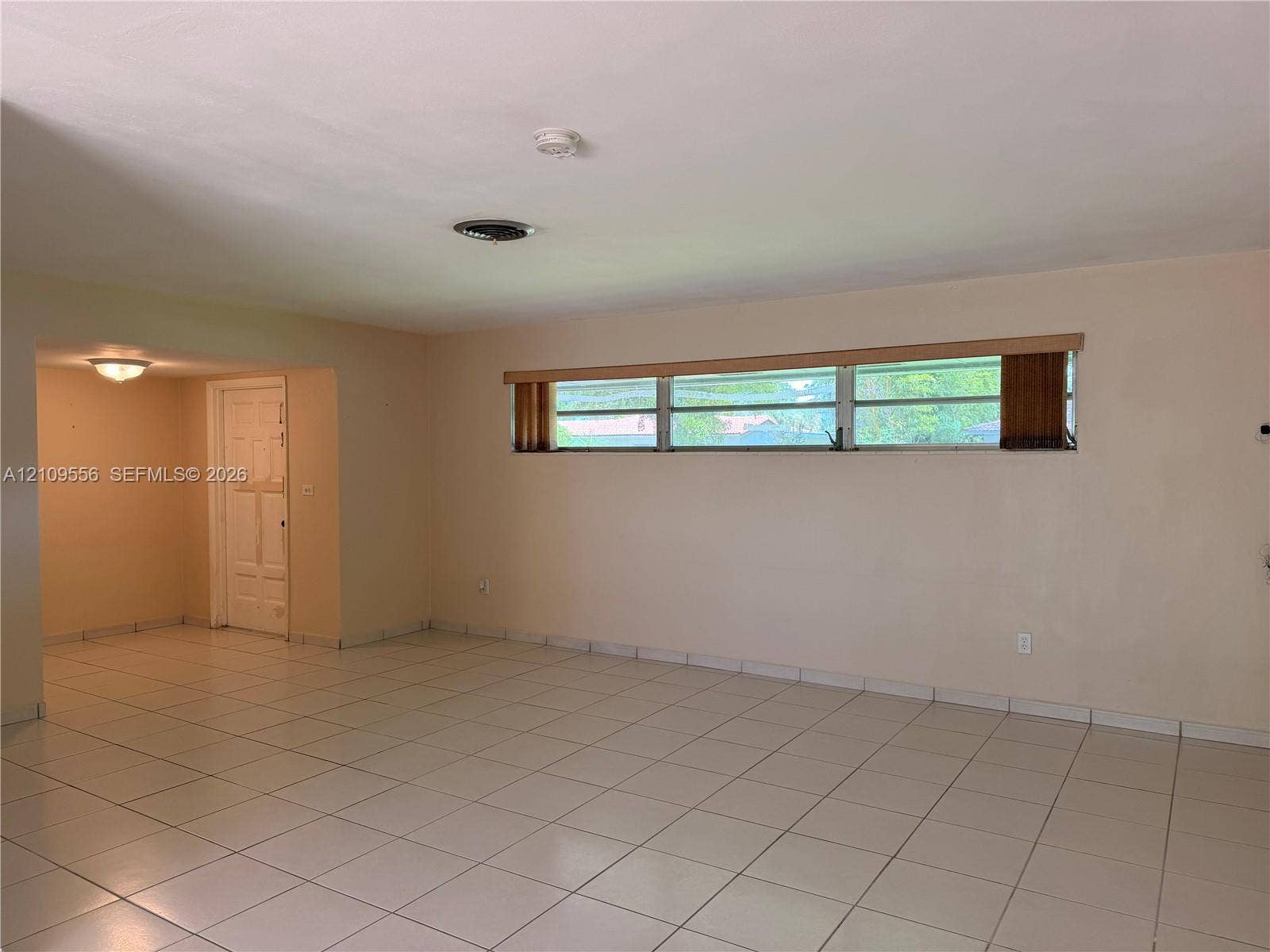 Interior space featuring neutral wall tones, ceramic tile flooring, horizontal window configuration, and recessed ceiling lighting