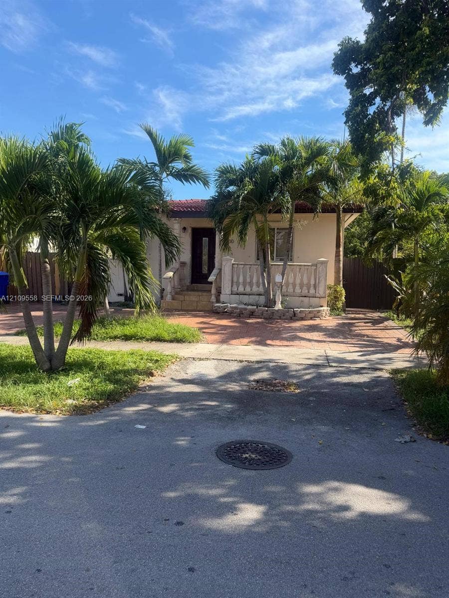 2800 SW 11th Street, Miami, FL 33135 Stucco exterior featuring a covered front porch with decorative balustrade, red tile roof accents, and paver driveway