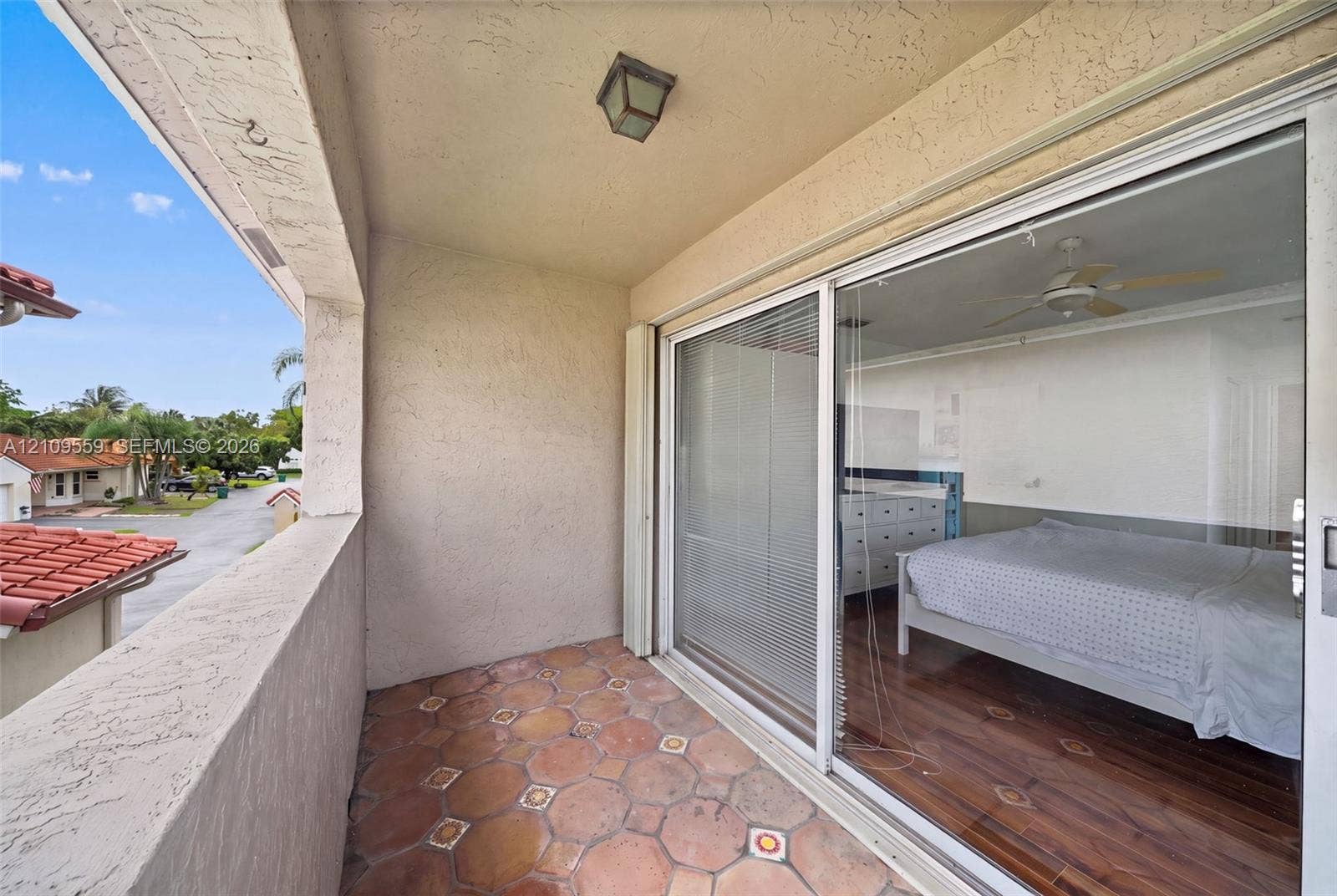 10217 NW 56th Street, Doral, FL 33178 Covered balcony featuring patterned terra-cotta tile flooring, stucco walls, and sliding glass patio doors