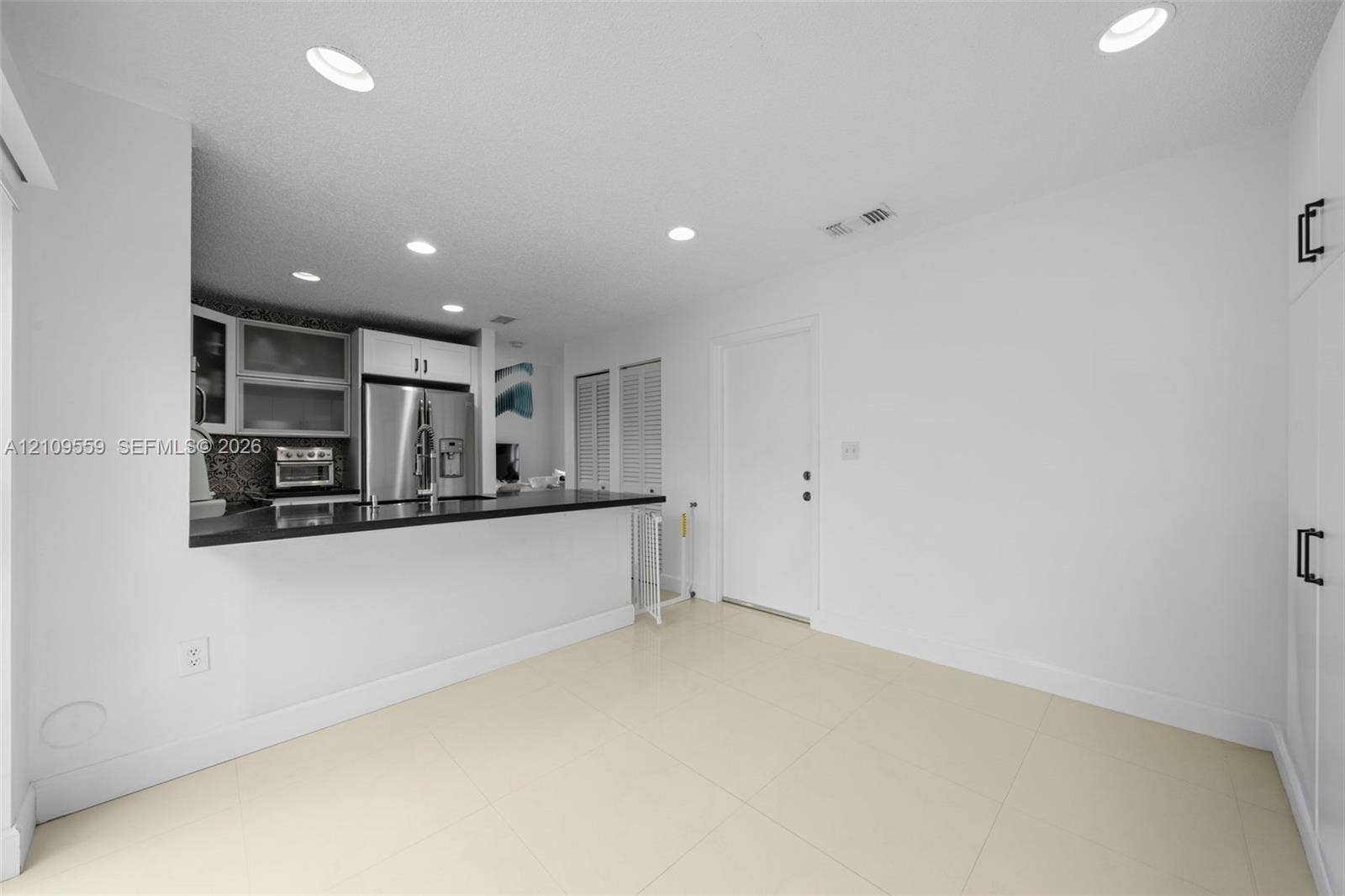10217 NW 56th Street, Doral, FL 33178 Kitchen featuring a breakfast bar with dark countertop, stainless steel refrigerator, recessed lighting, tile flooring, and floor-to-ceiling built-in cabinetry