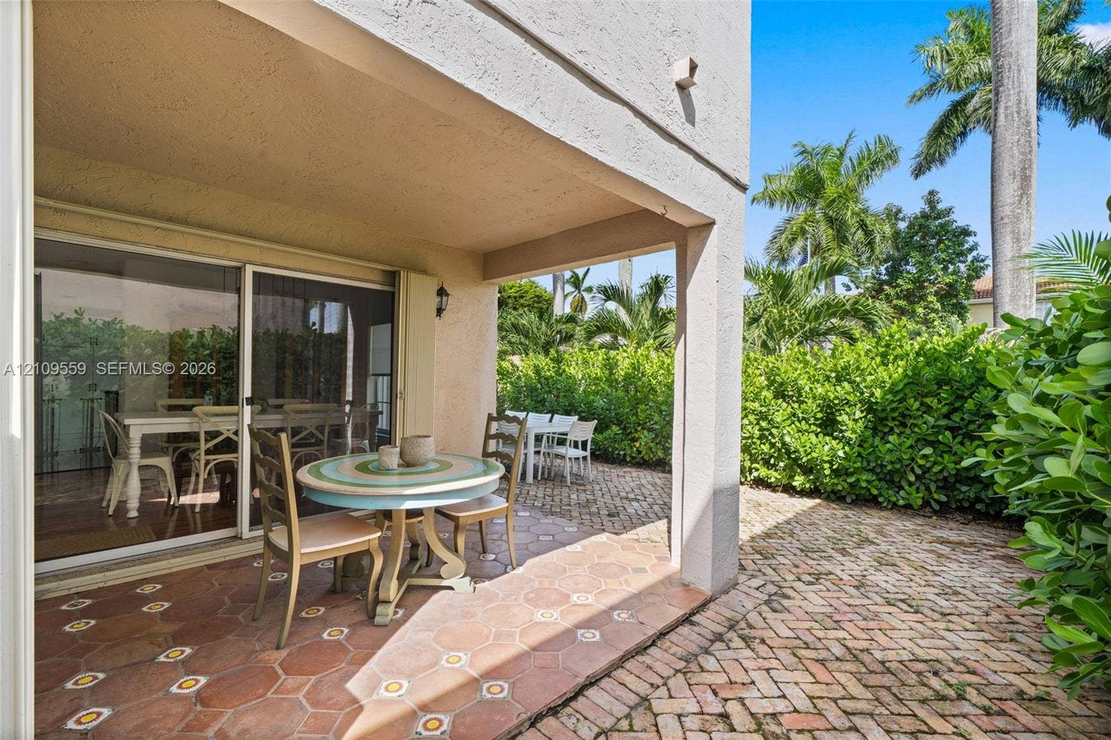 10217 NW 56th Street, Doral, FL 33178 Covered terrace featuring terracotta hexagonal tile flooring, brick paver patio, and sliding glass door entry