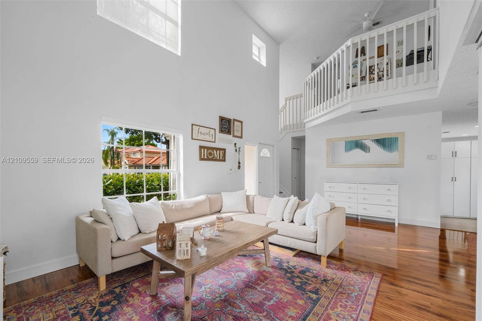 10217 NW 56th Street, Doral, FL 33178 Two-story living area featuring vaulted ceilings, a prominent multi-pane window, and an interior balcony with a white railing