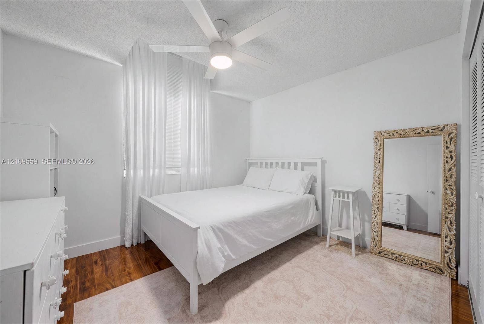 10217 NW 56th Street, Doral, FL 33178 Bedroom featuring wood-finish flooring, a white ceiling fan with integrated lighting, and louvered closet doors