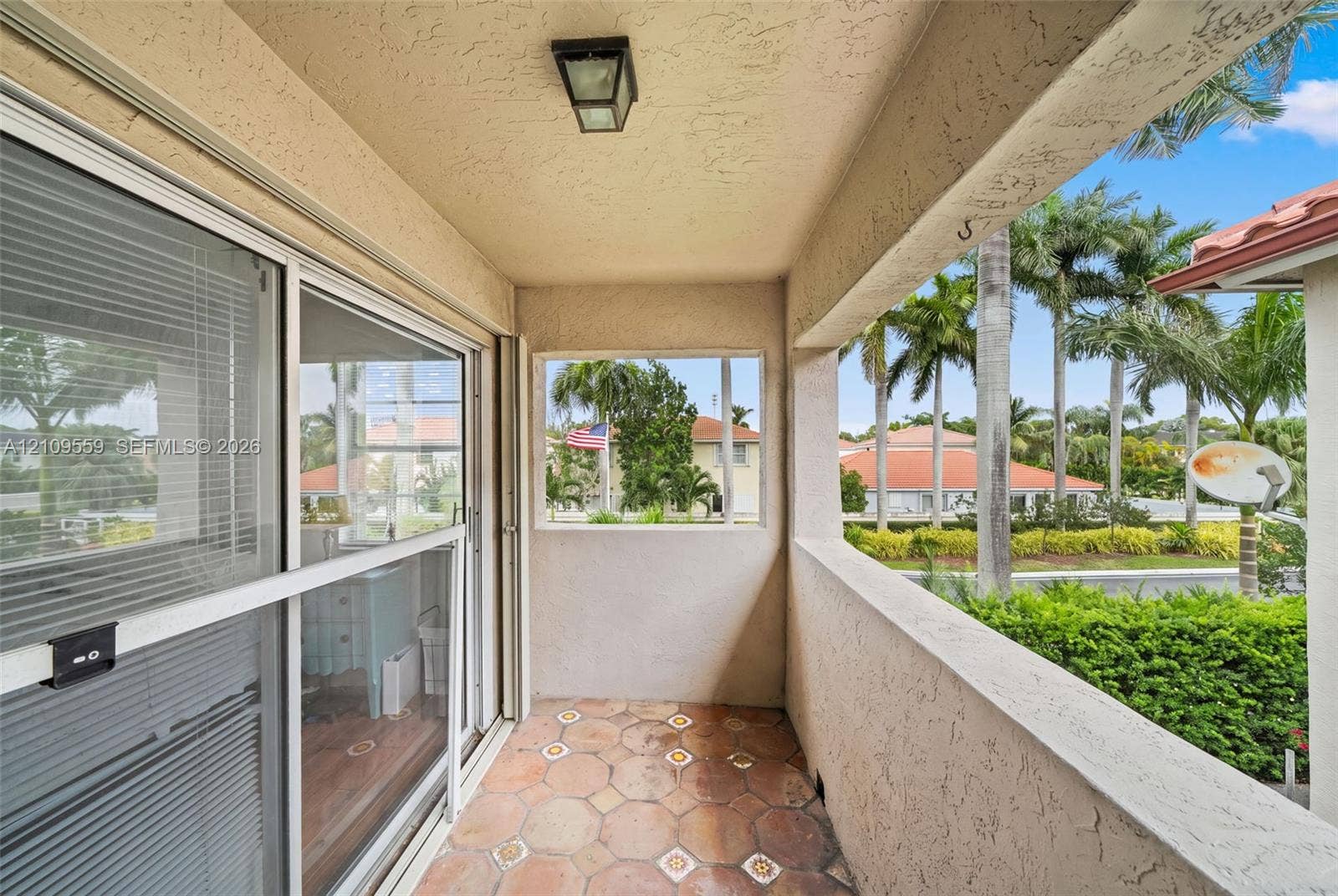 10217 NW 56th Street, Doral, FL 33178 Covered balcony featuring hexagonal tile flooring, textured stucco walls, and sliding glass doors